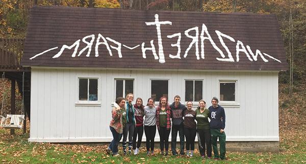 students on a service learning trip with "Nazareth Farm" painted on the roof